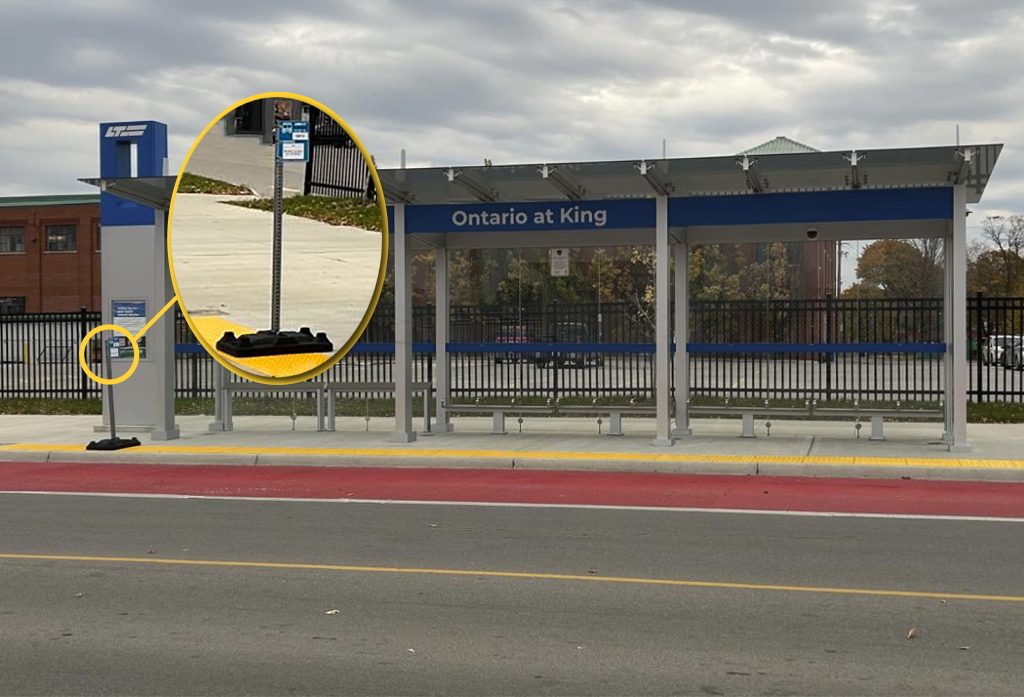 The image is a photo at the Ontario & King Rapid Transit Stop. In the photo the temporary bus stop pole on a rubber base which has a call out of the stop to show more clearly the cane detectable base.